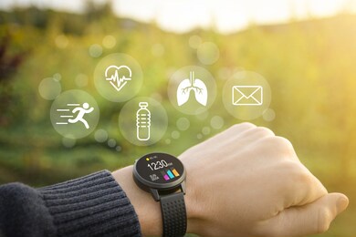 smart watch, fitness tracker on hand in the outdoor on a blurred green background with icons of basic functions.concept of the technology to check health. close up
