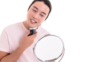 asian male model shaved his beard with electric shaving machine. isolated on white background
