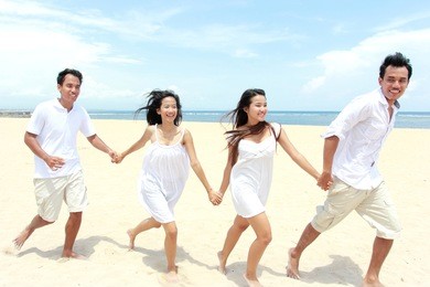 group of young friends enjoying beach together holding each others