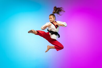 practice. karate, taekwondo girl with black belt isolated on gradient background in neon light. little caucasian model, sport kid training in motion and action. sport, movement, childhood concept.