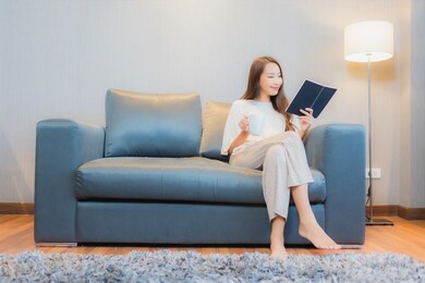 portrait beautiful young asian woman read book on sofa in living room interior