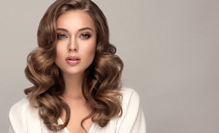 beauty  woman in a white shirt with long  and   shiny wavy  hair .  beautiful blonde   woman model with curly hairstyle .