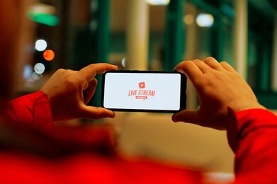a man watches a live broadcast on a smartphone screen. button live stream on the screen of a mobile phone