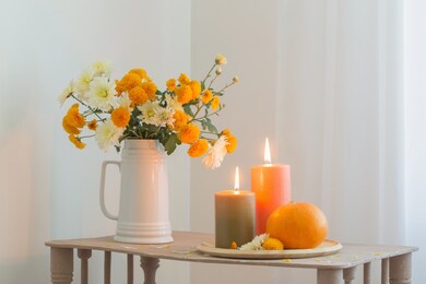 autumn flowers with burning candles and pumpkins on vintage wooden shelf