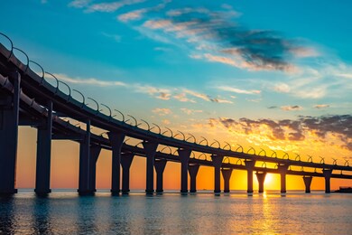 bridge silhouette on background of sunset. cityscape with sunset. silhouette of bridge over evening bay. bridgework silhouette on a summer evening. double car bridge over bay. bottom view