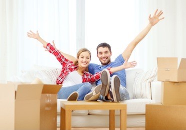 moving, home and couple concept - smiling couple relaxing on sofa in new home