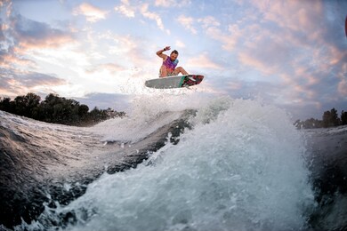 active man engaged in extreme water sports and jumps high above the wave on the surf style wakeboard.
