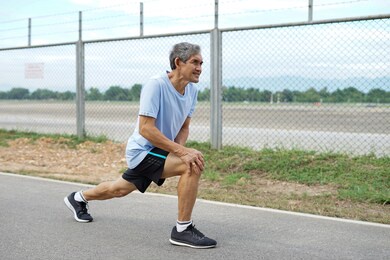 elderly retired man is stretching his legs before running or jogging, concept warm up exercise prevent injury in elderly people         