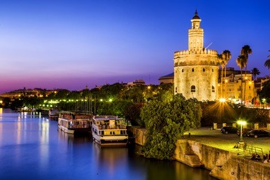 view of golden tower (torre del oro) of seville, andalusia, spain over river guadalquivir at sunset 