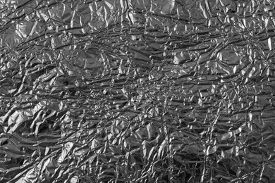 shiny crumpled aluminium foil texture. full frame of silver metalized pattern close up 