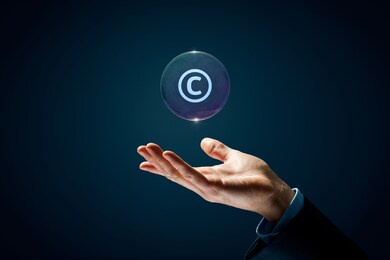 copyright, patents and intellectual property protection law and rights. hand with soap bubble (symbol of dream) with symbol of the copyright inside.