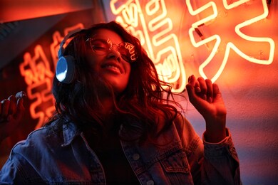 happy cool fashion funky african young black hipster lady wears trendy glasses headphones listening dance pop dj music standing in neon night club light at style party. translation: chicken laugh