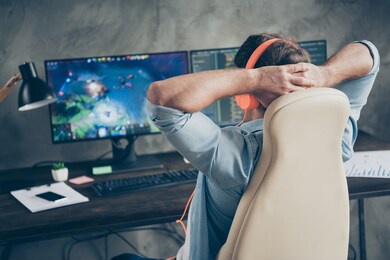 rear back behind view of his he nice focused guy geek playing web network game remote freelance resting sitting in chair at modern industrial interior loft concrete wall style work place station