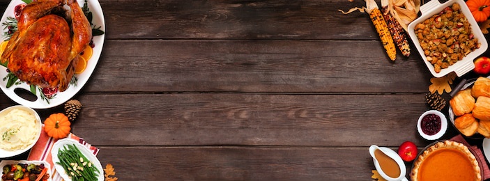 traditional thanksgiving turkey dinner. top view double border on a dark wood banner background with copy space. turkey, mashed potatoes, dressing, pumpkin pie and sides.