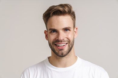 joyful handsome guy smiling and looking at camera isolated over grey background