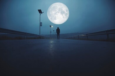 a man walking on the asphalted road at night in the a full moon night, fantasy futuristic concept.