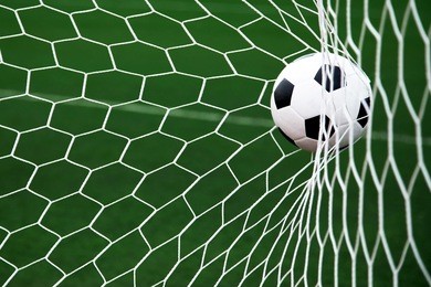 soccer ball in goal net with green grass 