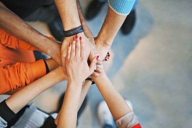 multiethnic group of young people putting their hands on top of each other. close up image of young students making a stack of hands.