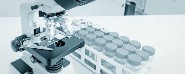 science microscope on lab bench. microbiology laboratory. blue toned image of binocular microscope. water sampling procedure for microbiological analysis