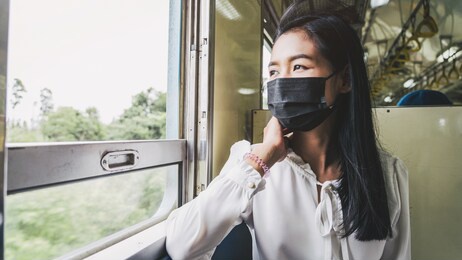 young asian woman looking out of window while sitting in the train.