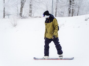 snowboarder with closed face rides on the track in snowy weather
