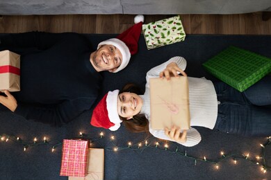 high angle view of a hispanic couple relaxing at home and sharing christmas gifts while lying on the floor