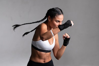 determined middle aged woman boxer preparing for boxing fight. fitness mid adult woman preparing for boxing training at gym. beautiful strong sportswoman in boxing gloves prepared right hand punch.