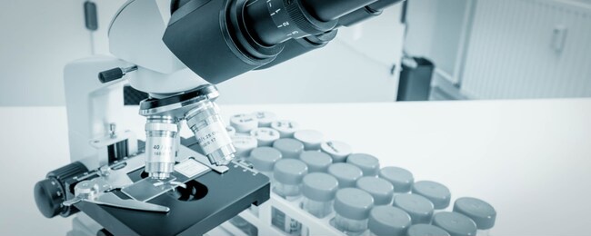 science microscope on lab bench. microbiology laboratory. blue toned image of binocular microscope. water sampling procedure for microbiological analysis