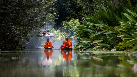 buddhist monk in small wooden boat sailing in canal for receive food in morning, the culture tradition buddhist monk of making merit to monks morning, popular tourist attraction on canals of thailand.