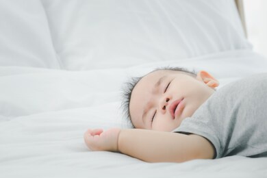 cute 7 months asian baby girl is sleeping on bed in the morning.newborn little child sleep have nice dream.