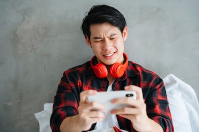asian young businessman playing mobile game on smartphone with serious looking.