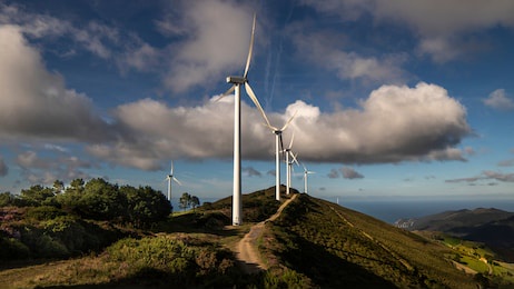 wind generators, road to energy transition on a hill and a background of clouds