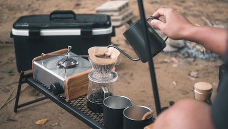 hand drip coffee in the camp, a man pouring water on coffee ground with filter.drip coffee and camping.