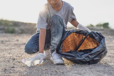 kids volunteer help garbage collection charity environment. improving environment. energetic male volunteer using garbage bag while collecting litter