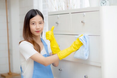 young asian woman in gloves cleaning home in room, housekeeper is wipe with fabric, housemaid and service, worker polish dust at living room in house, housework and domestic, lifestyle concept.