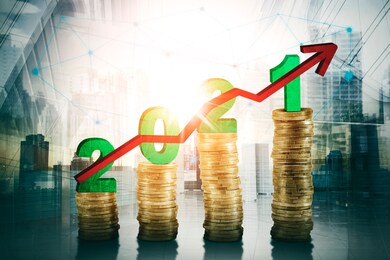 double exposure of number 2021 above pile of gold coins shaped growth chart and arrow upward with modern city background