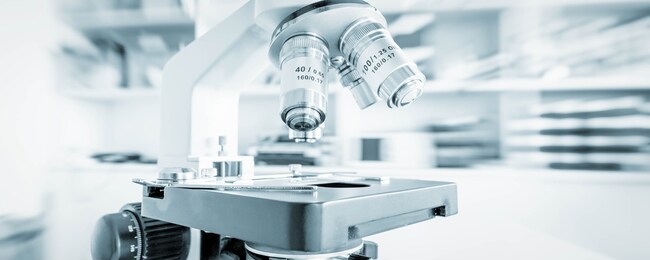 science microscope on lab bench. microbiology laboratory. blue toned image of binocular microscope