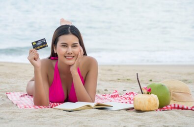 asian beauties wearing swimsuits holding credit cards and sunbathing on the beautiful sandy beach on vacation.summer holiday and comfortable to spend concept.