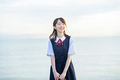 asian high school student showing a smile and the background of the sea
