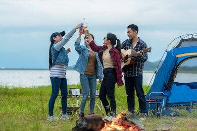 party camping new year.  group asian family and friends travel enjoy party and roasted sausages relax in vacations. campfire at touristic camp at nature in outdoor forest. 