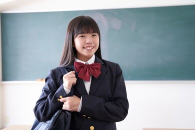 a japanese junior high school girl holding her school bag in the classroom