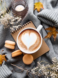beautiful and romantic autumn composition with  cup of coffee, warm blanket, decorative striped pumpkins, candles and autumn leaves. cozy morning. hygge home interior.