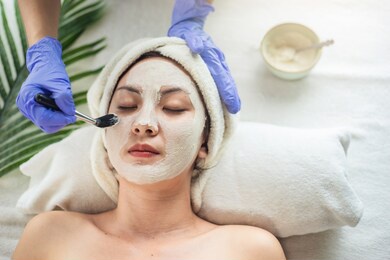 asian woman getting facial face care by beautician at spa salon, closeup face female applying clay mask by beautician. young woman beauty treatment.