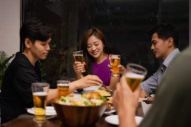 working group of young asians drinking beer and clink glasses in a restaurant. they're relaxed.