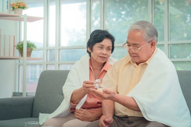 retired asian couple is taking care of each other by reminding them to take medicine in cold winter