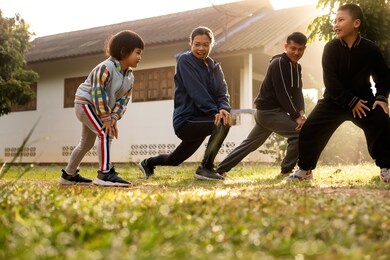asian little girl warming up in the early morning with multi generation family at countryside home yard, stretching bodies workout before running together. healthy lifestyles concept.