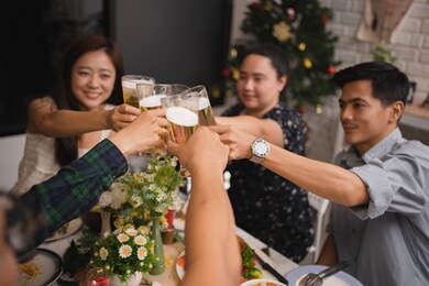 group of asian people clink glasses at a party at home. they are very happy and fun.