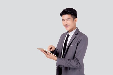 portrait young asian business man in suit standing using tablet computer to internet isolated on white background, businessman confident touch screen digital pad with success, communication concept.