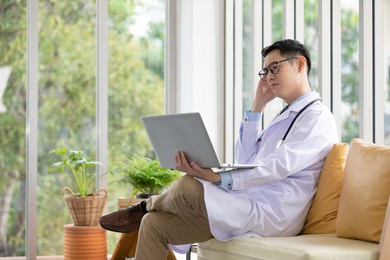 asian doctor using laptop computer and thinking something 