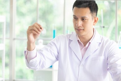 young man scientist with pen writing on the board in a laboratory
